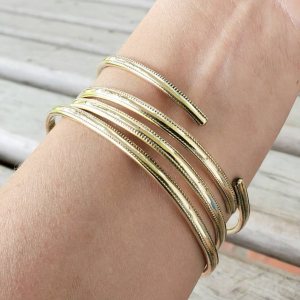 Stack of textured jeweler's brass bangle bracelets on model's arm