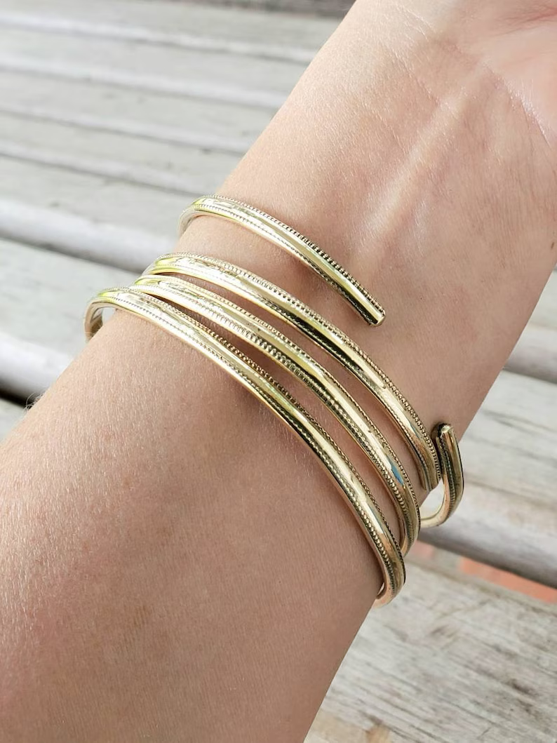 Stack of textured jeweler's brass bangle bracelets on model's arm