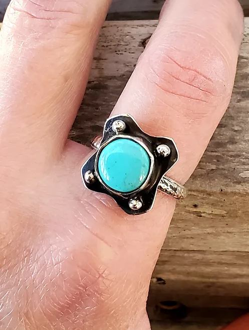 Round Turquoise cabochon set in darkened sterling silver with 4 sterling beads and a textured sterling band.