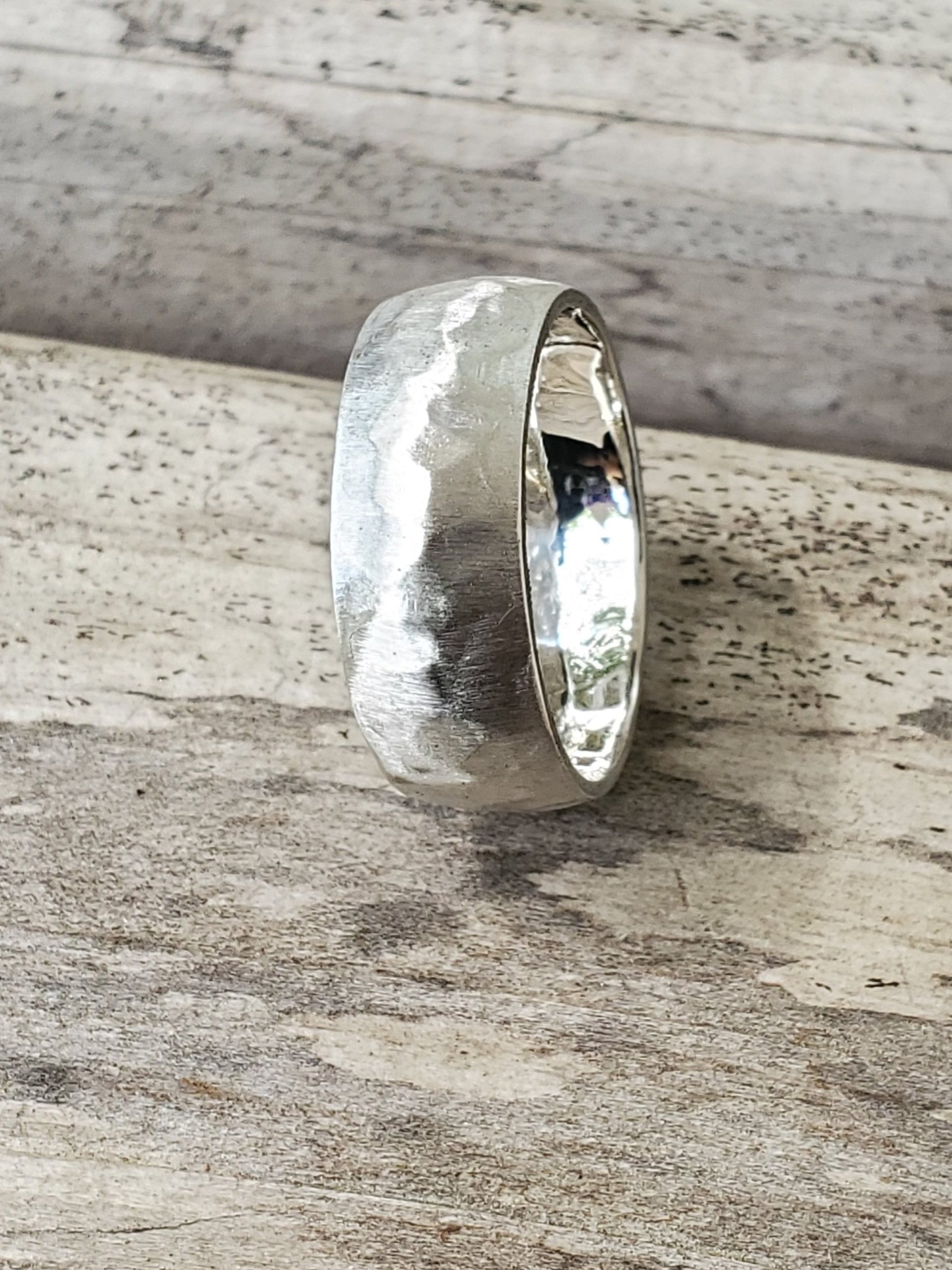 Satin Sterling Silver Hammered Domed Ring with Polished Interior on a wooden surface