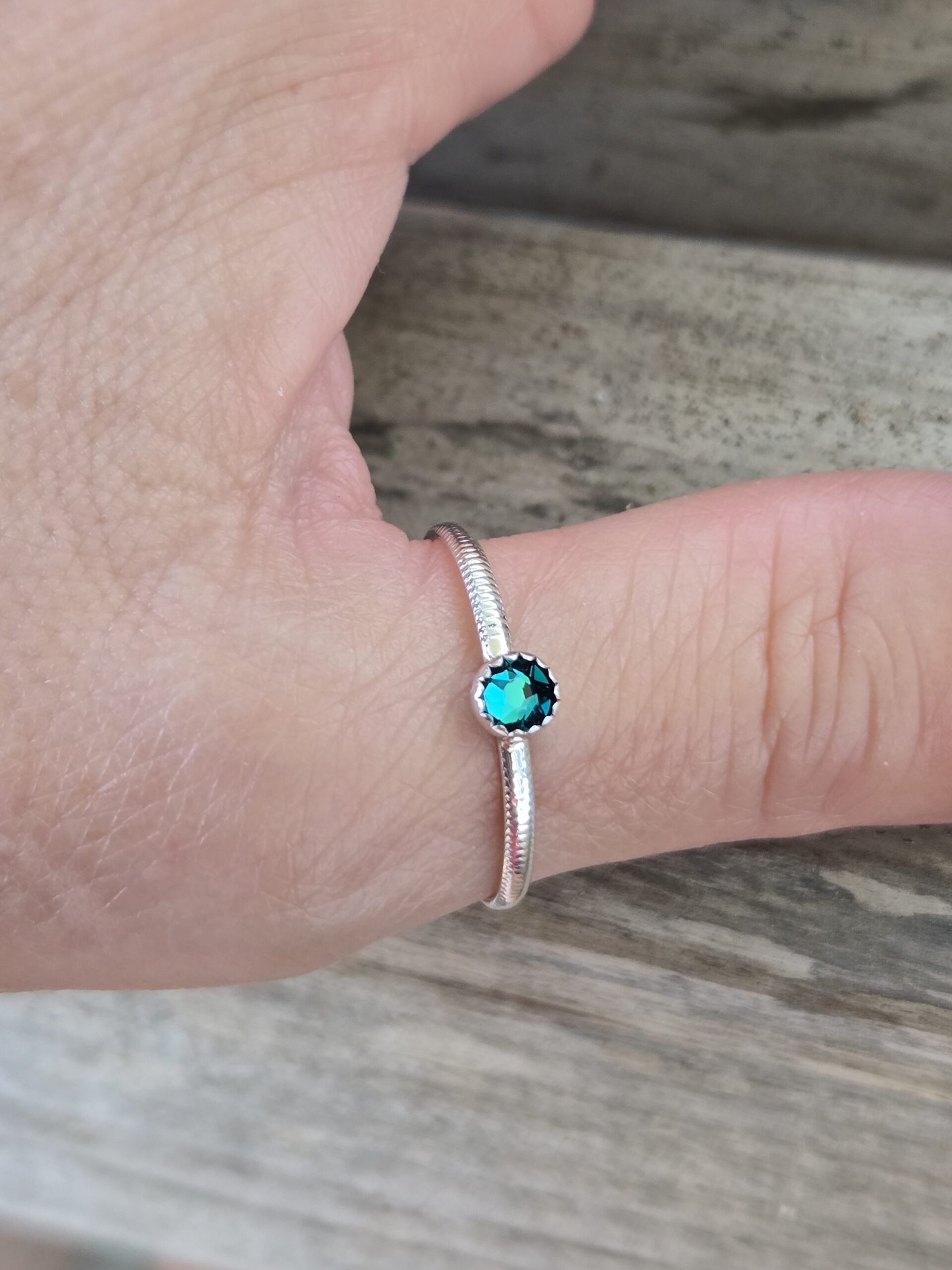 Slim Textured Sterling Silver Gemstone Stacking Ring shown on a model's thumb with a small blue topaz crystal