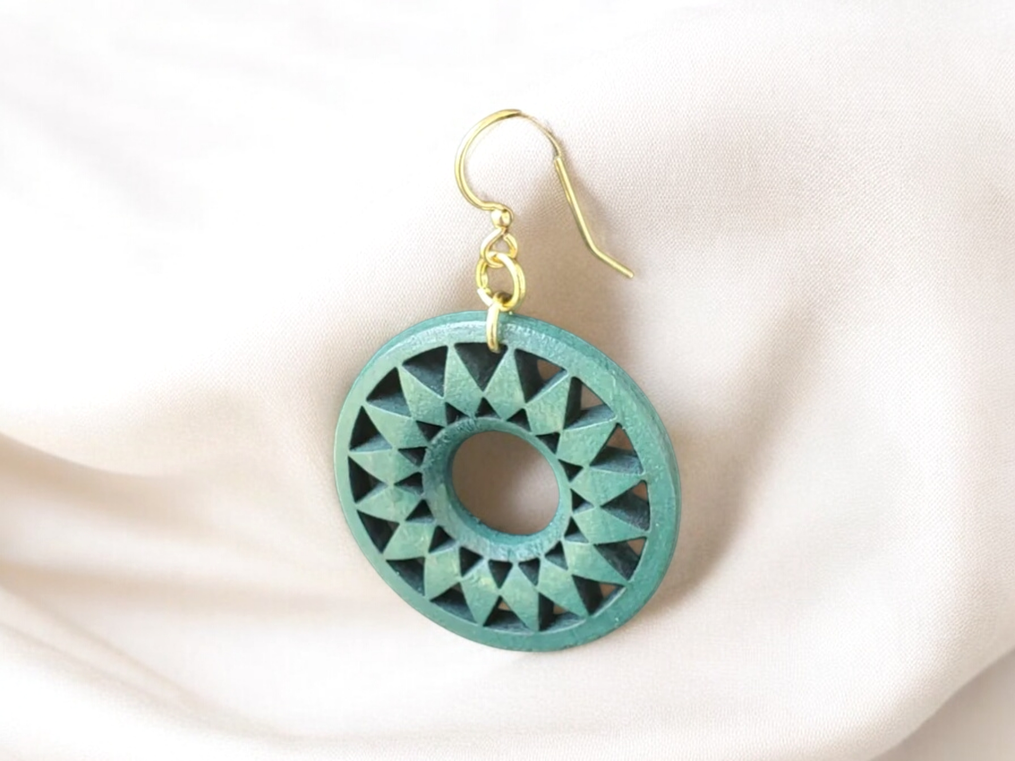Green Round Patterned wood discs on golden french wire earrings over a white background