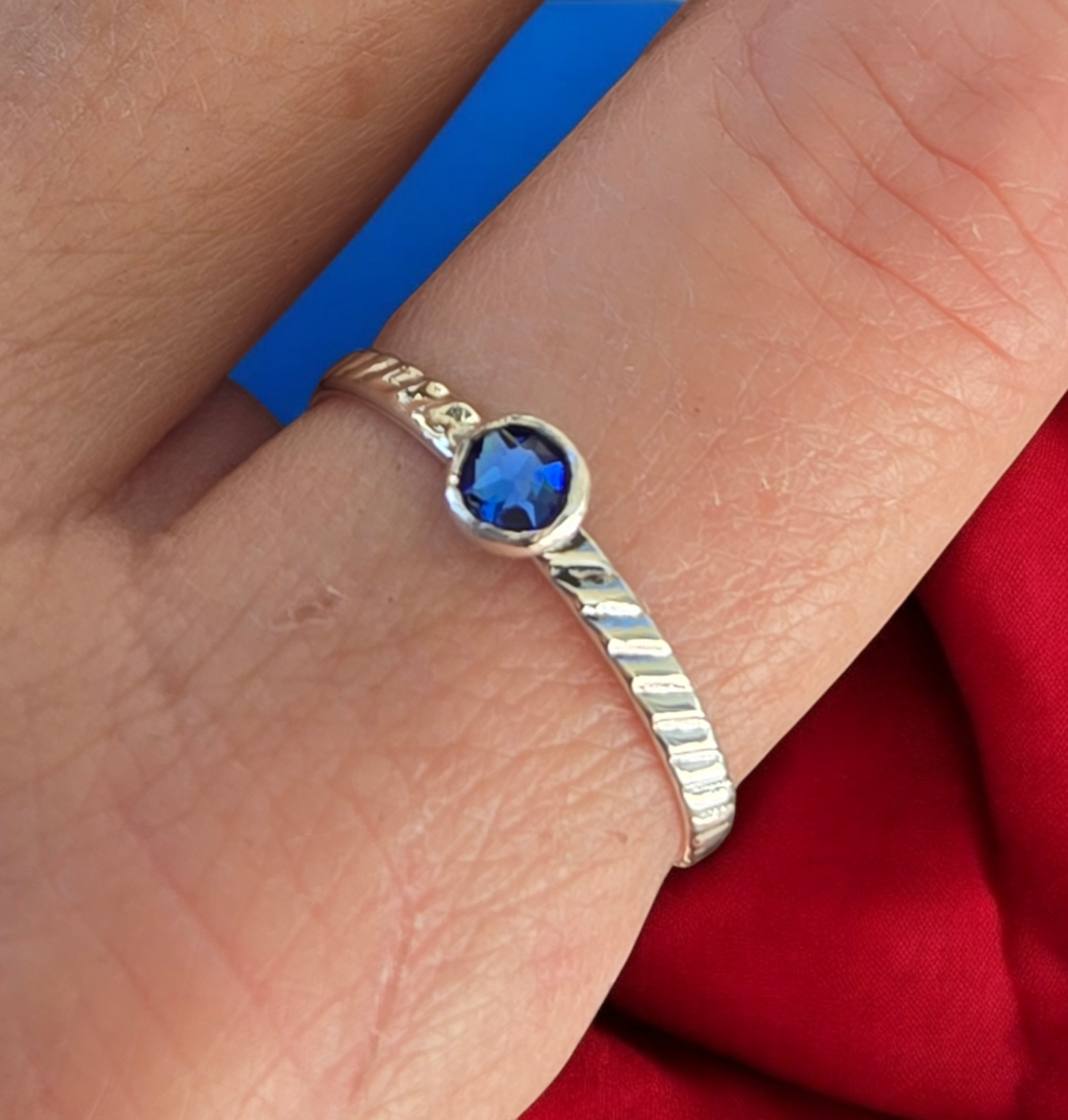Slim Textured Sterling Silver Gemstone Stacking Ring shown with a round, blue, sapphire crystal on model's finger