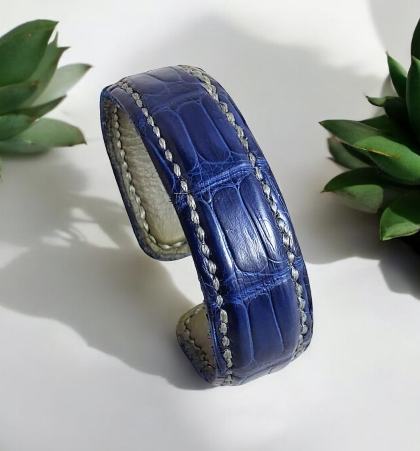 Blue Alligator Leather Bracelet Cuff Bracelet on a white background surrounded by succelents