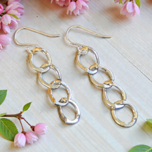 Oval Link Sterling Silver French Wire earrings shown surrounded by pink flowers and green leaves to enhance the beauty of the link earrings.