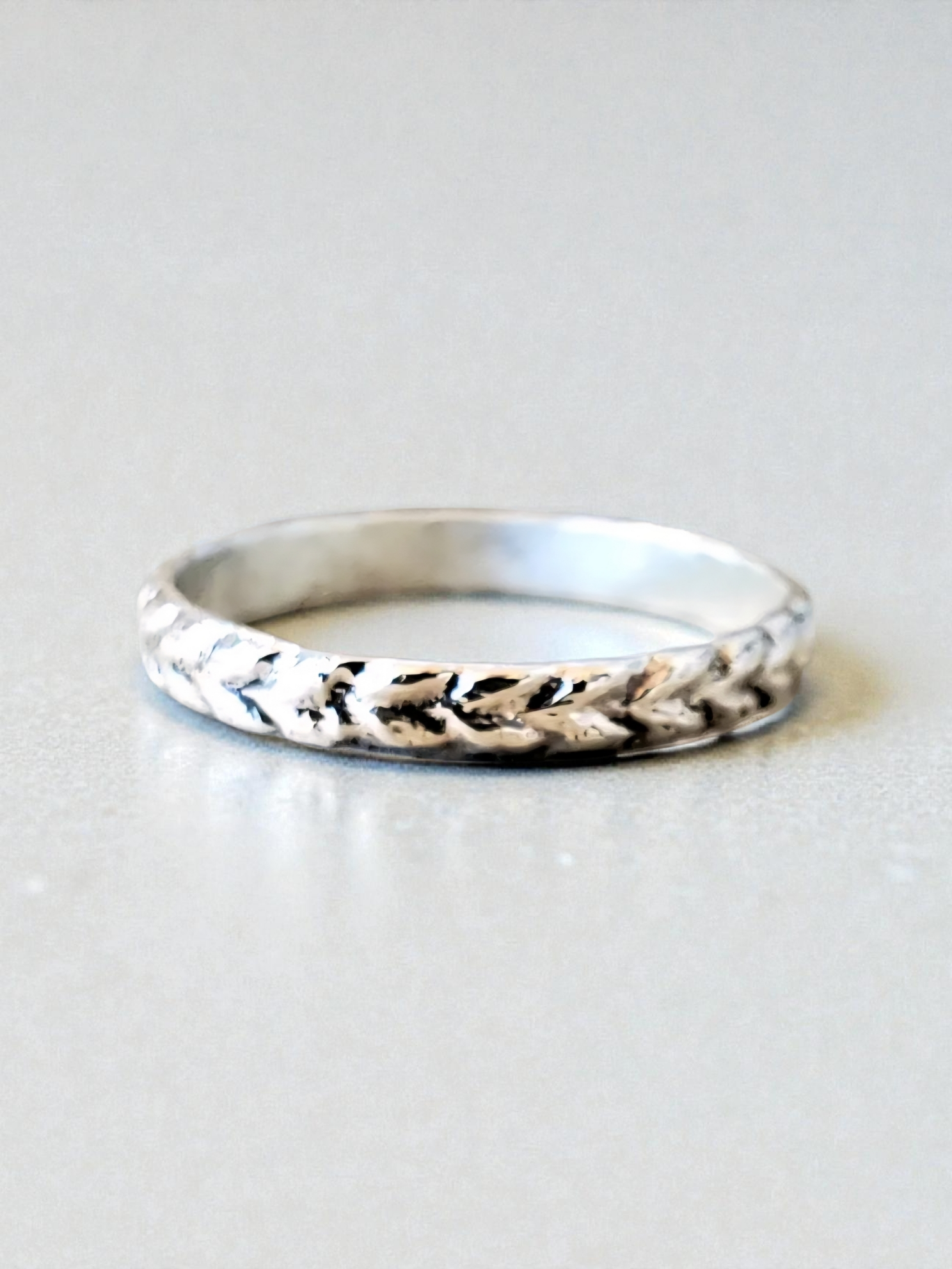 Slim Herringbone Patterned Sterling Silver Stacking Ring from front view showing a smooth band on the inside of the ring and the texture on the outside of the ring