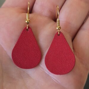 The maker holding her red Leather Teardrop Earrings.