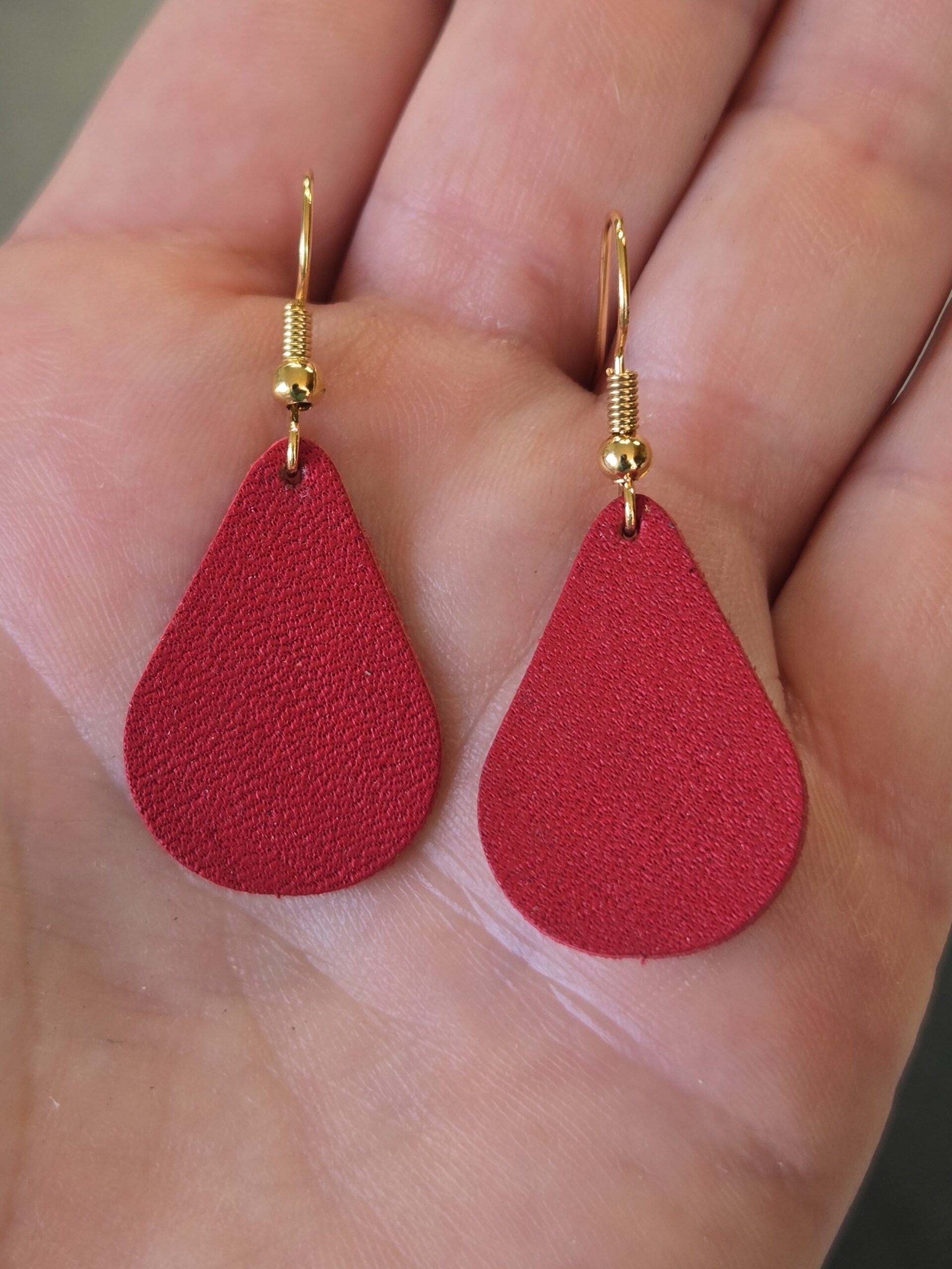 The maker holding her red Leather Teardrop Earrings.