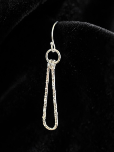 Textured silver wire teardrop on French wire earrings on black fabric background.